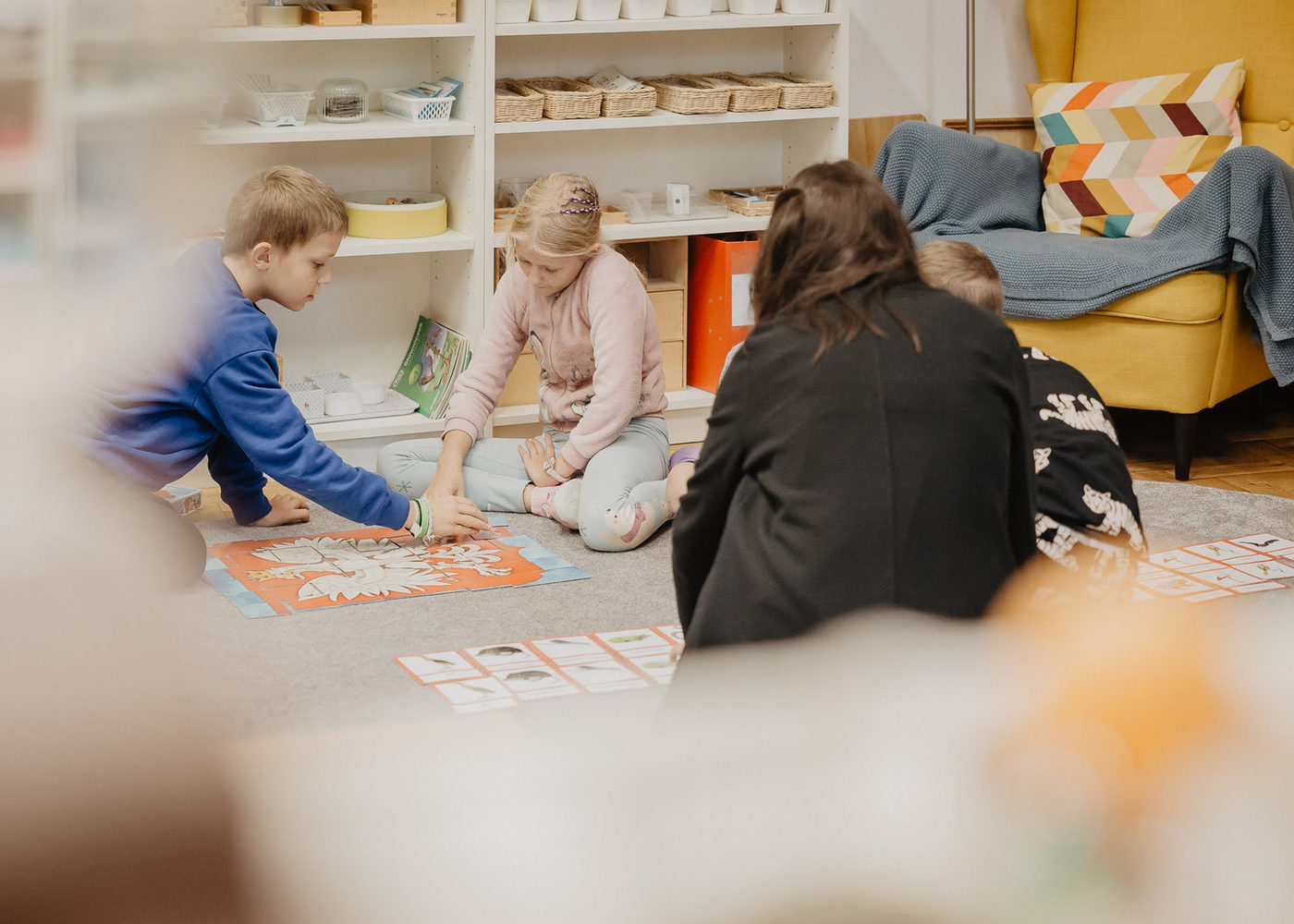 Dzieci pracujące z materiałami Montessori na dywanie